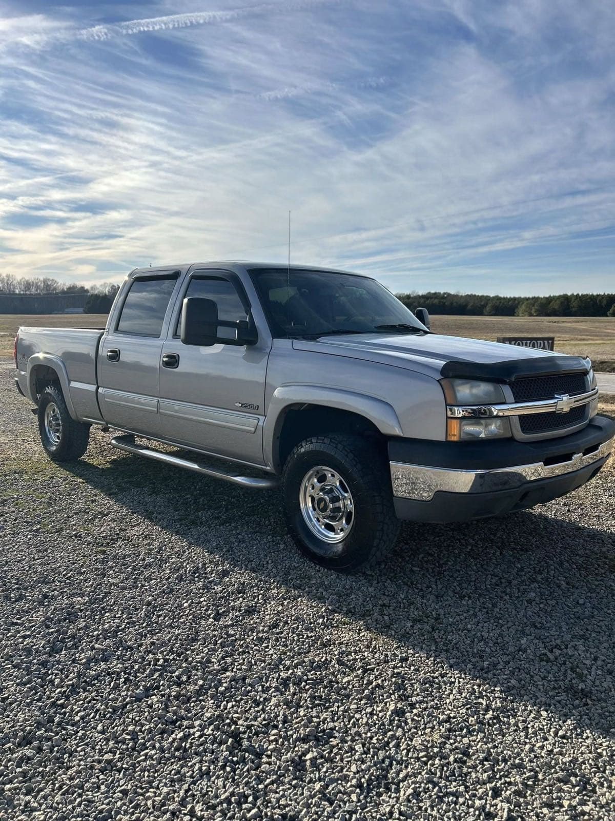 Silver Chevy Silverado 2500 detailed with glossy paint on gravel lot